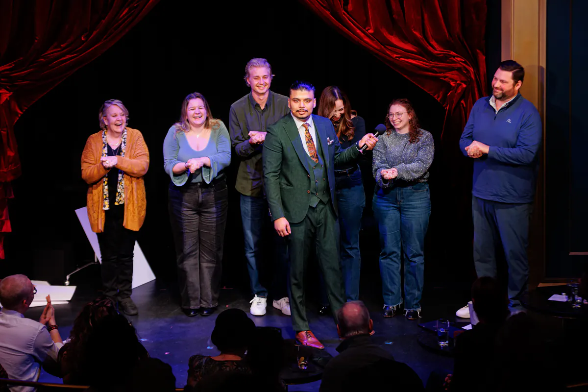 Savio Joseph on stage with a line of volunteers from the audience